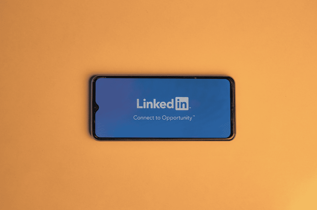 A smartphone showcasing the LinkedIn logo and Connect to Opportunity slogan rests on an orange surface, a perfect symbol for any digital marketing agency striving to expand their network and unlock new prospects.